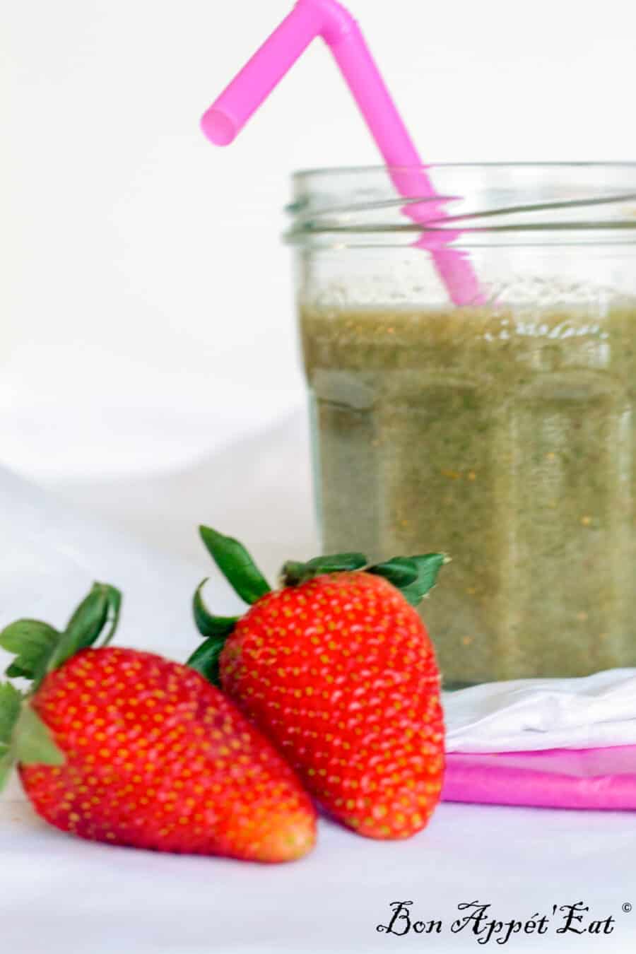 Green Smoothie in a jar with a strawberry in front. 