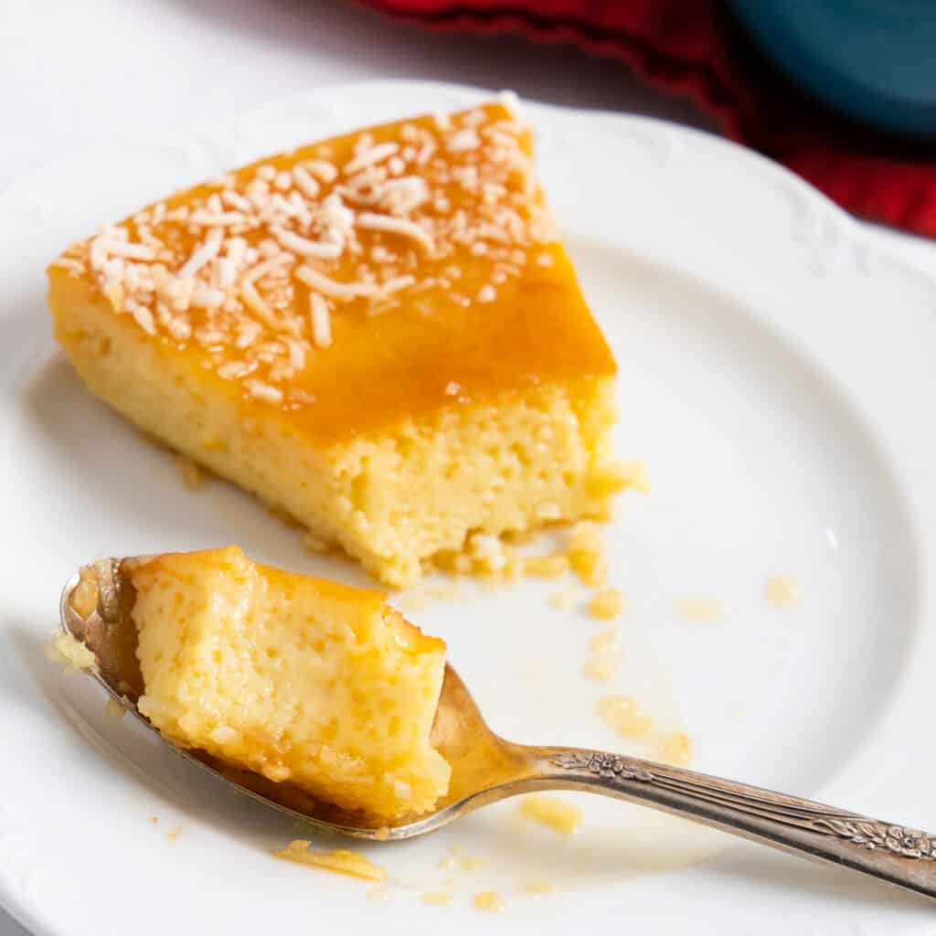a slice of flan with a spoon and some flan in the spoon.