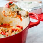 Easy and Delicious drumstick Basque Chicken on a spoon with a partial view of iron cast pot