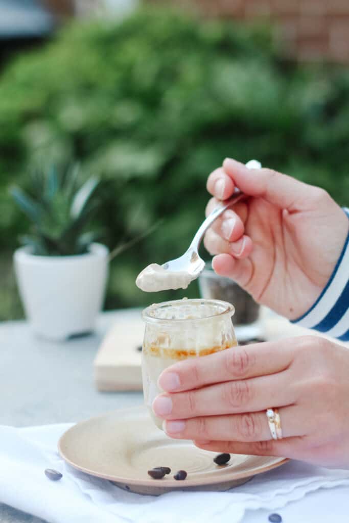 Hand scooping in a coffee pot de creme with whole coffee beans around, stripped sleeve