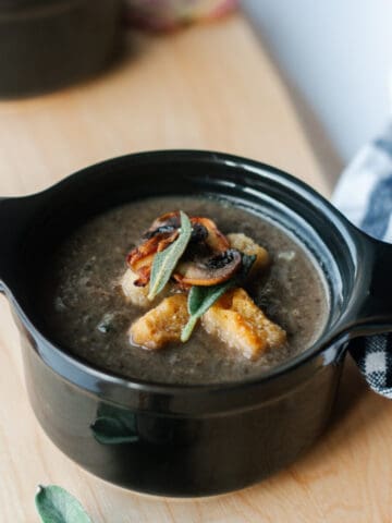 Dairy free sage mushroom soup in 2 individual black cocottes with fall leaves around