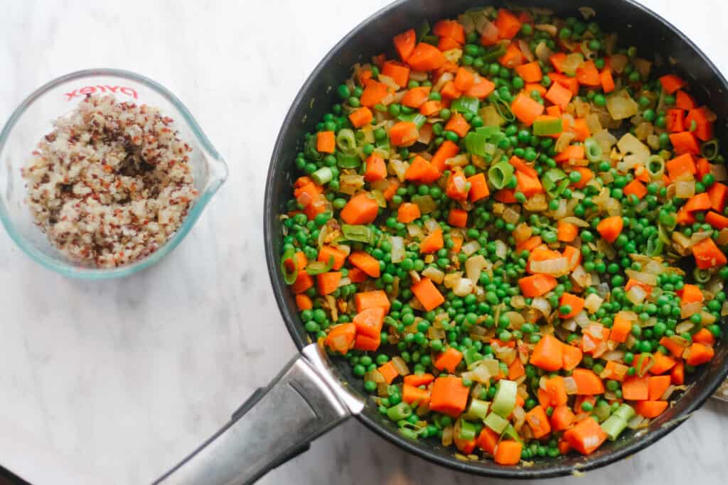 Quinoa Fried Rice: Cooked veggies in the pan with cooked quinoa on the side.