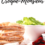 Stacked croque-monsieurs with a white bowl of salad in the back
