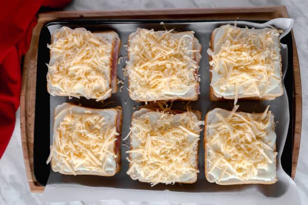 Top view of unbaked croque-monsieur sandwiches on a baking sheet.