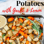 Top view of roasted carrots and potatoes in a baking sheet with half of lemon on the corner and a branch of rosemary.