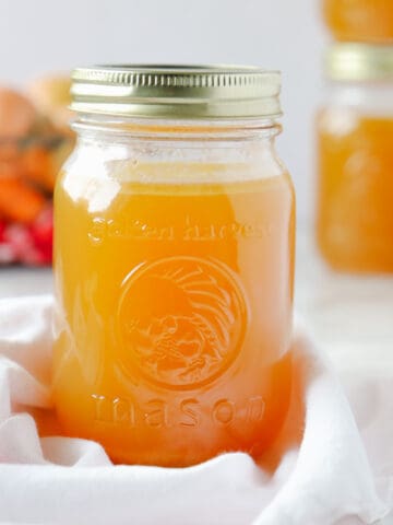 Close up of a Mason jar with broth in it and a few jars in the background