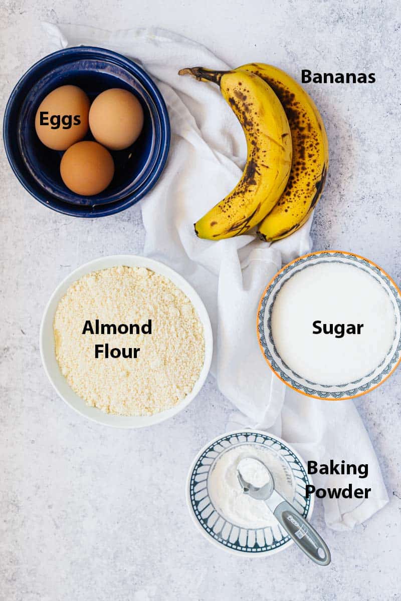 Top view of ingredients for almond flour banana muffins: eggs, bananas, almond flour, sugar and baking powder