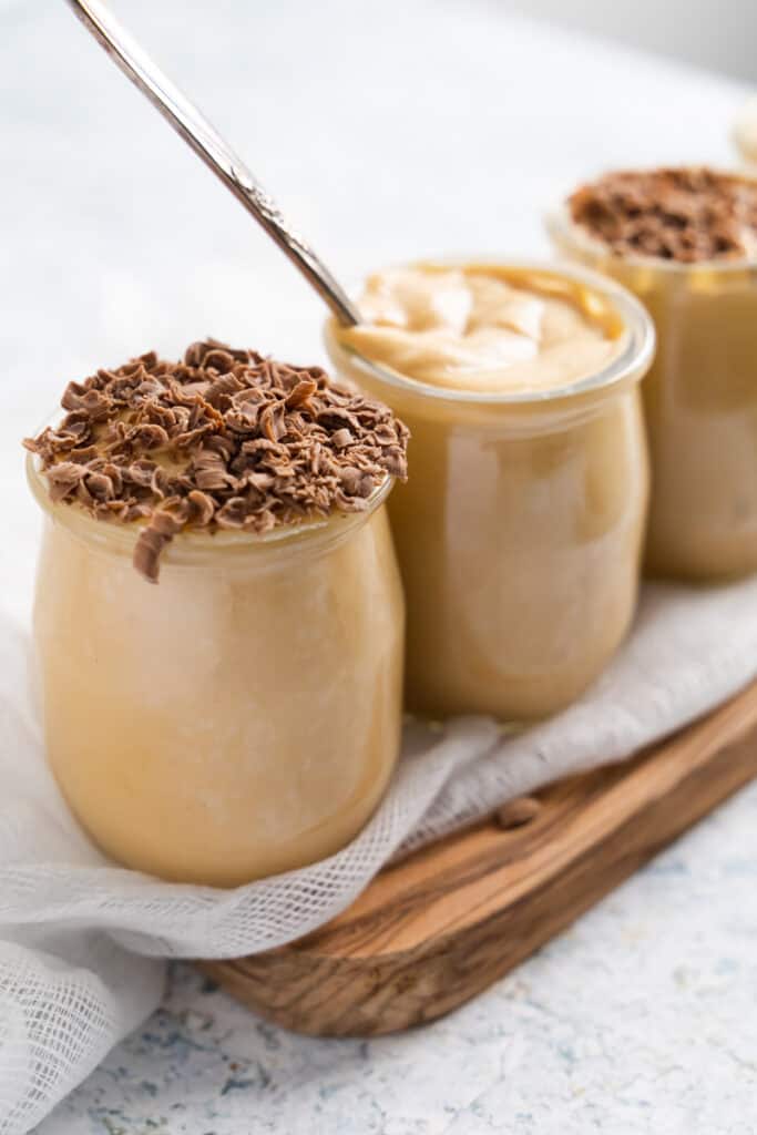 close up of 3 jars lined up in an angle with dulce de leche mousse in it.