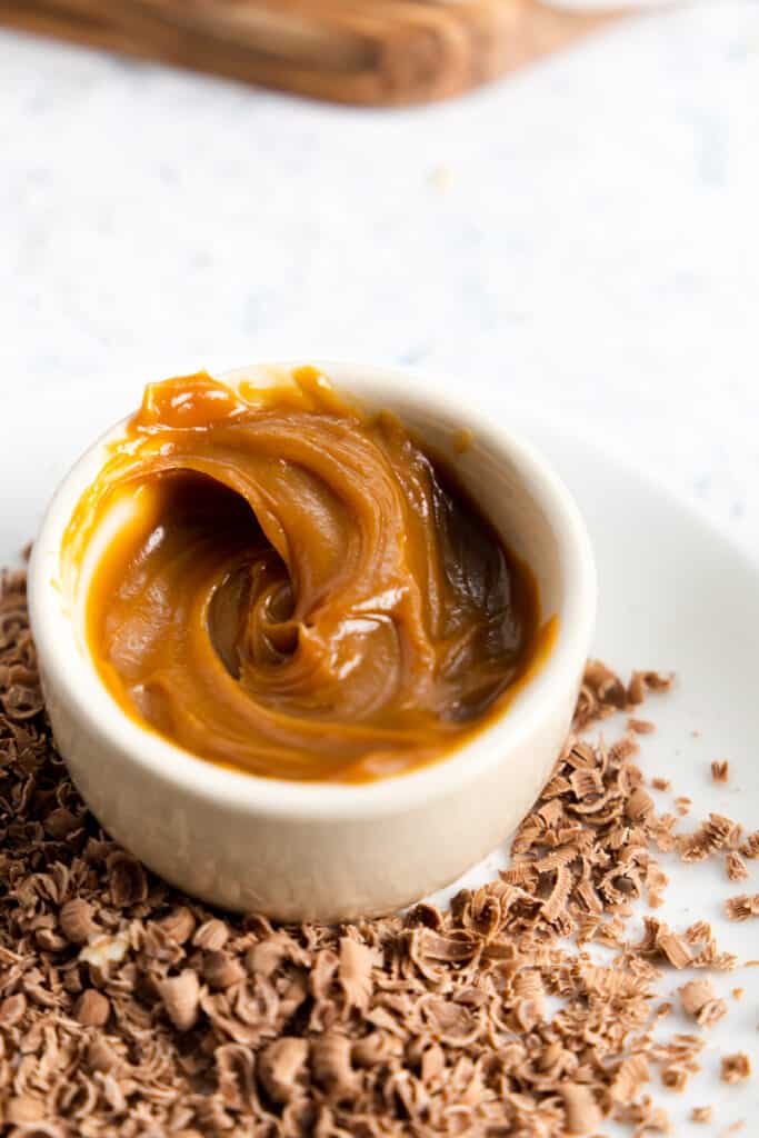close up of dulce de leche in a small beige ramekin