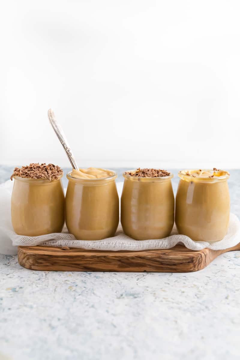 side view of 4 glass jars with dulce de leche mousse in it.