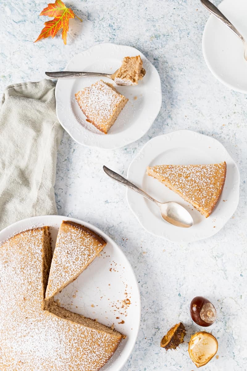 Top view of the chestnut cake and 2 small plates with a slice each in it with a spoon