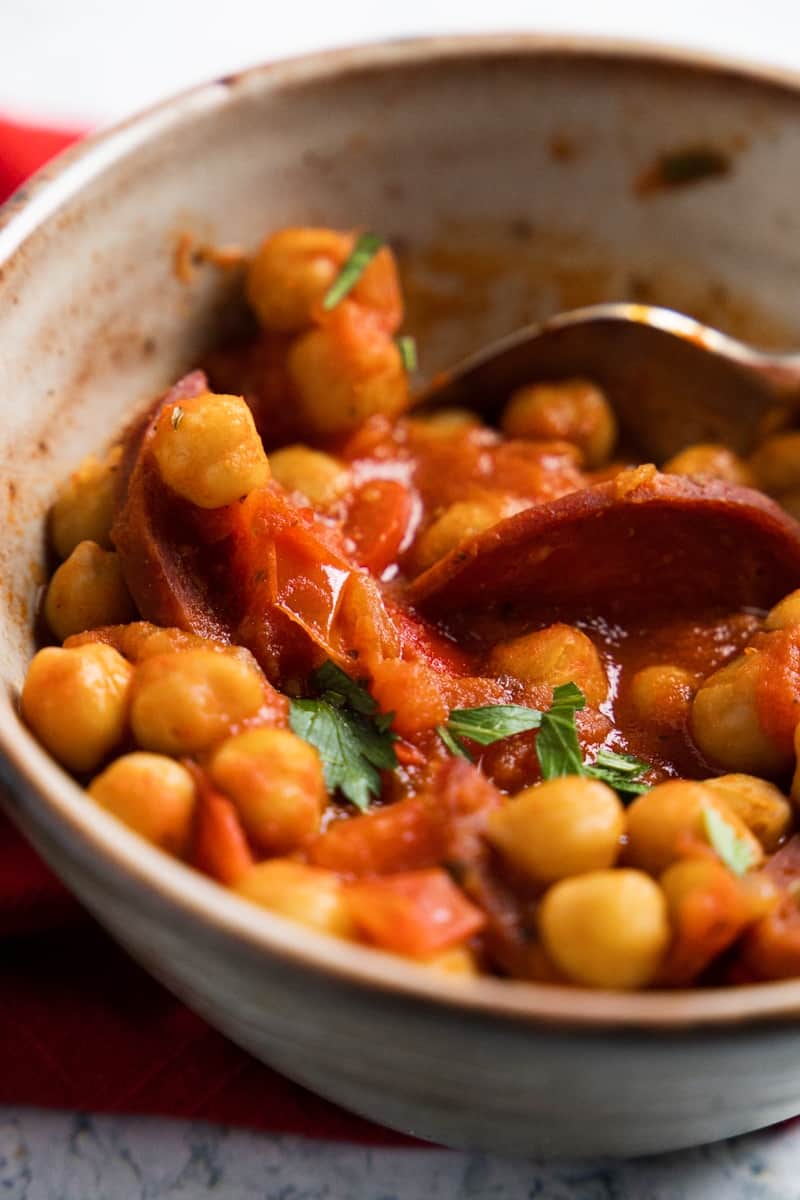 close up of chickpeas and chorizo in a beige bowl