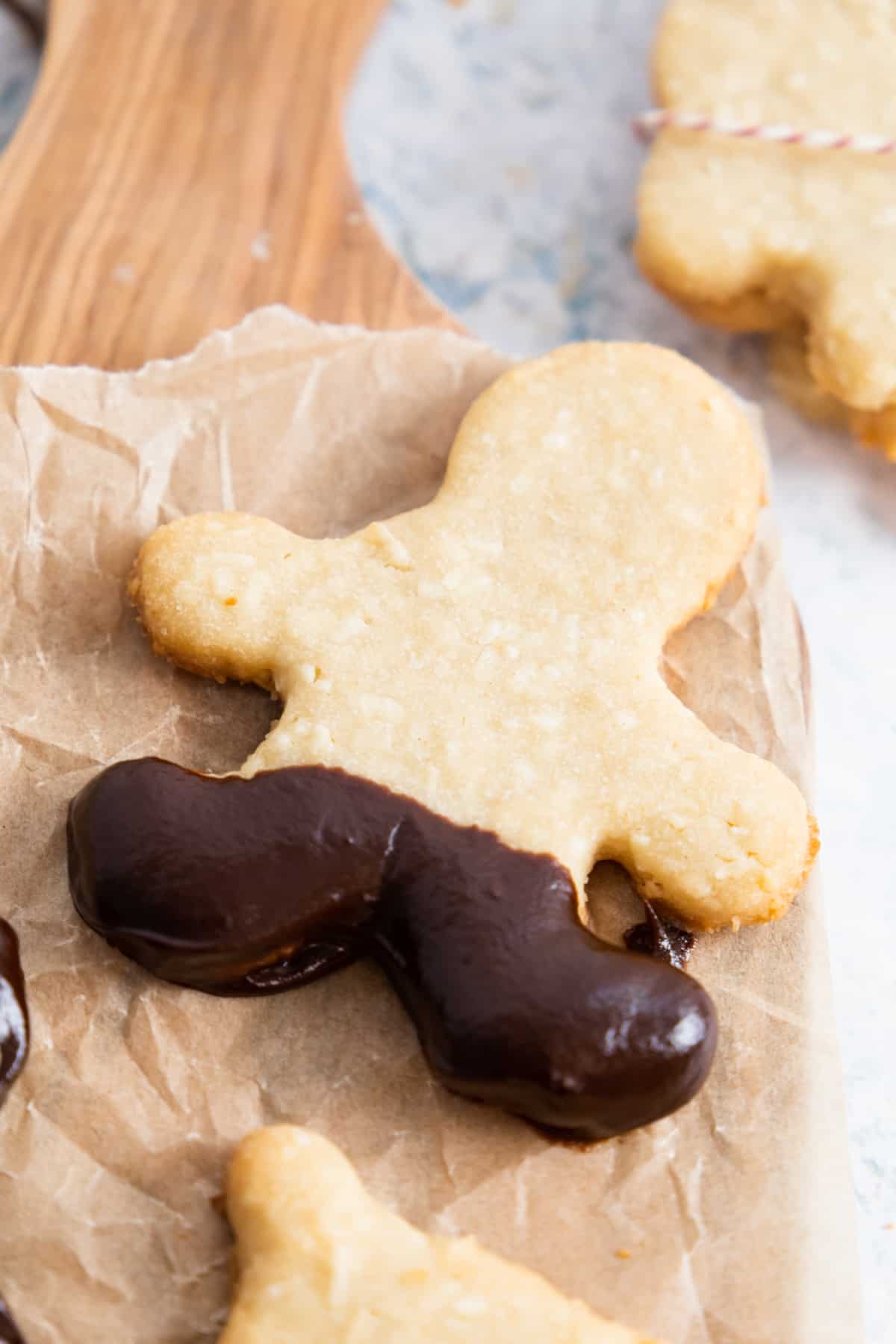 close up of a sugar cookie in a shape of a gingerbread man and the leg dipped in dark chocolate. 