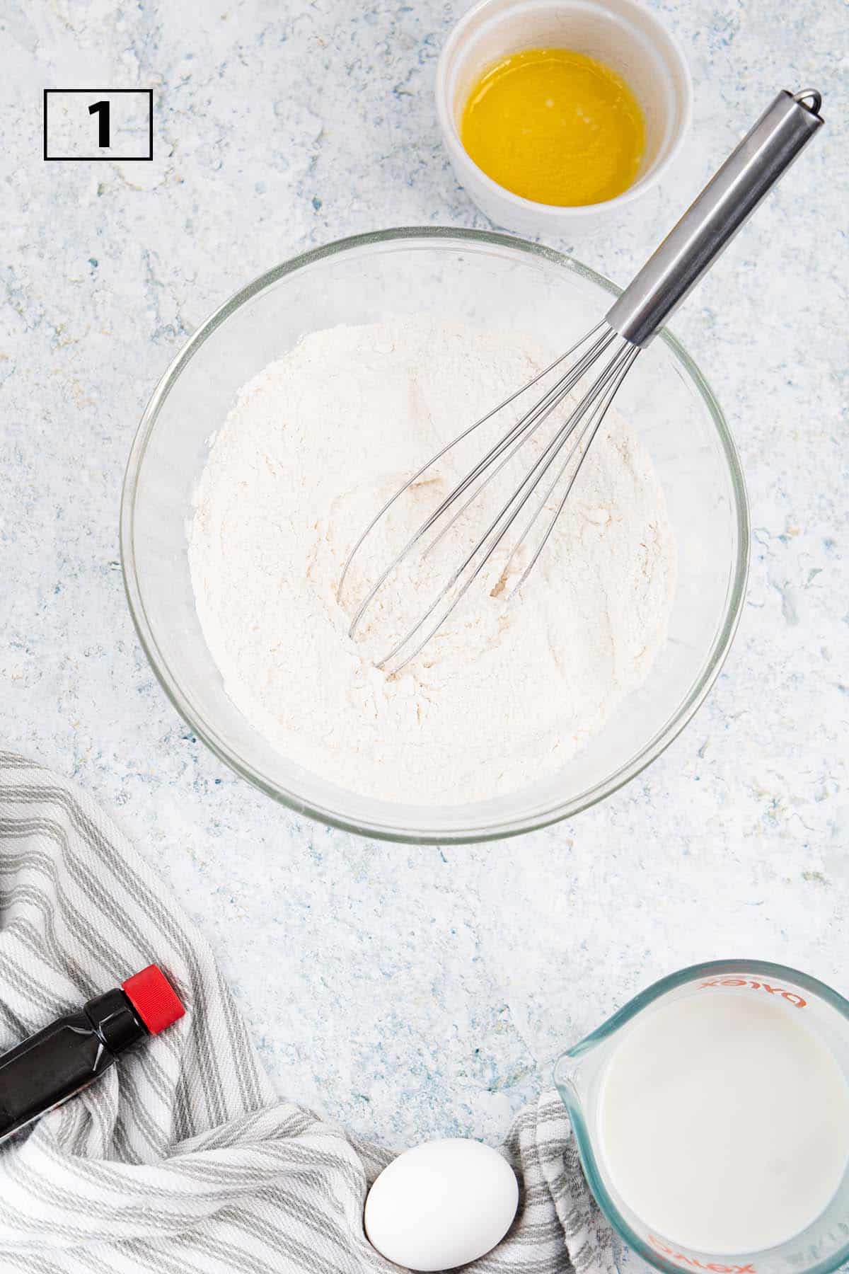 mixing bowl with dry ingredients and a whisk and a small mixing bowl.