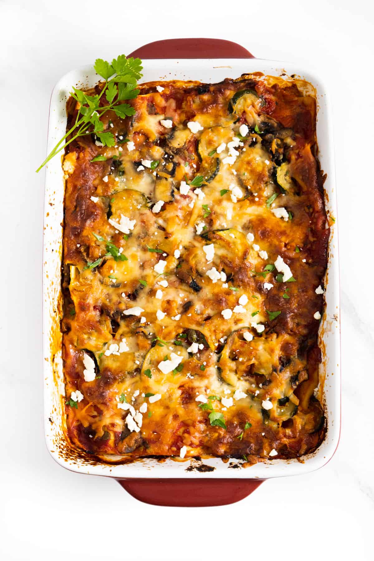 cooked lasagna with some feta and parsley on top.