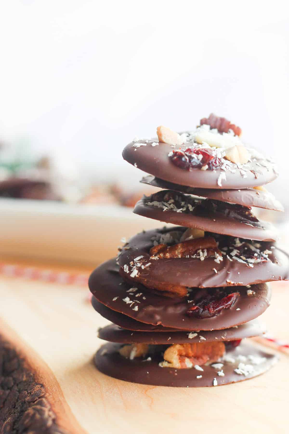 stack of round chocolate bark stacked on a piece of wood and a red.