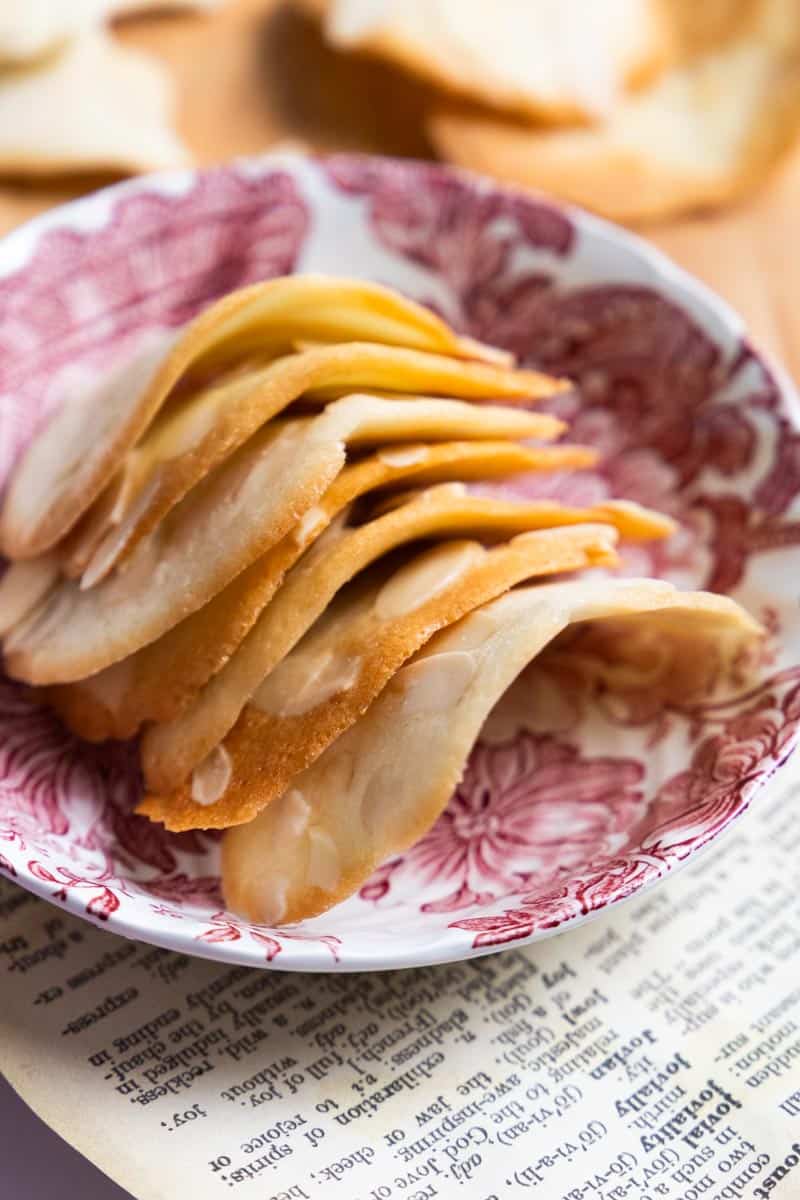 almond tuiles stacked in a shallow pink and white dish. 