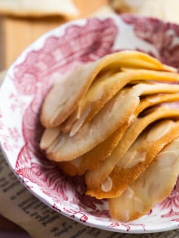 almond tuiles stacked in a shallow pink and white dish.