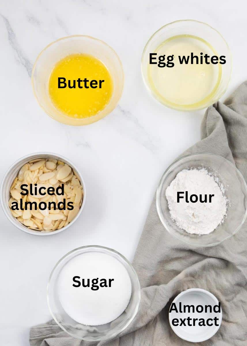 ingredients in a transparent bowl dish labelled: butter, egg whites, sliced almond, flour, sugar and almond extract. 