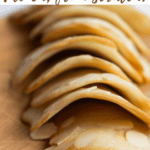 almond tuiles lined up on a wooden chopping board.