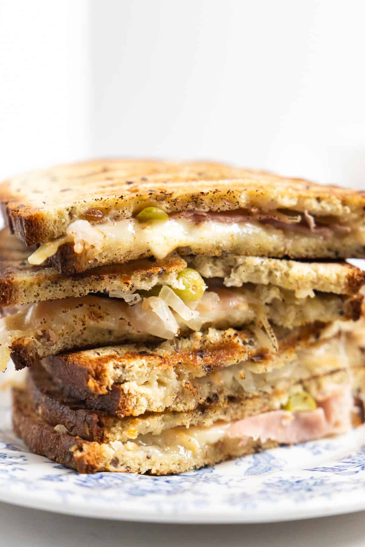 stack of grilled cheese with cold cuts and small pickles.