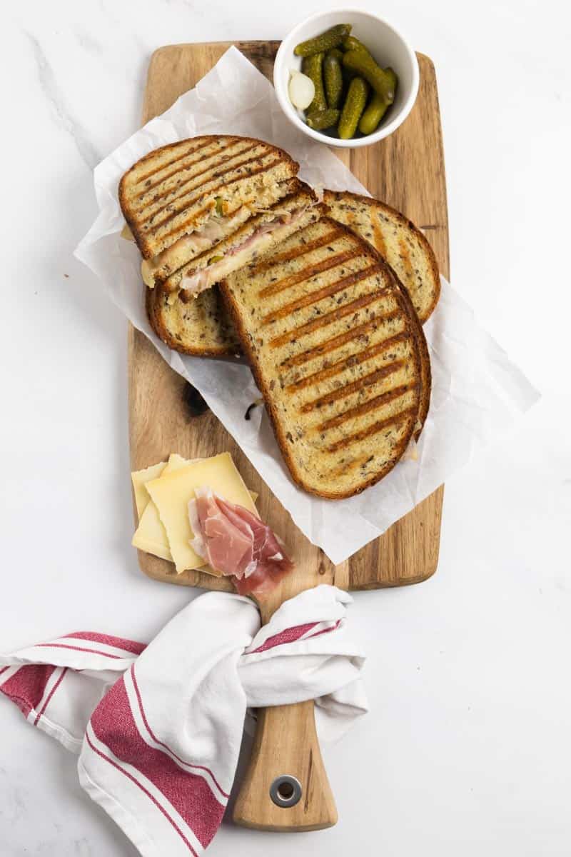 Grilled cheese on a wooden board with a white linen on the side.