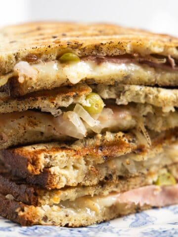 stack of grilled cheese with cold cuts and small pickles.