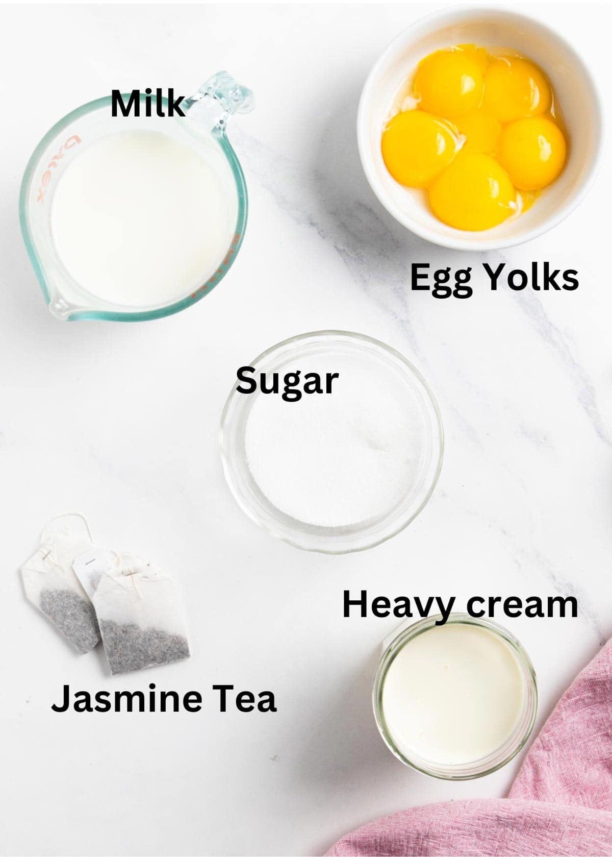 Ingredient labelled on a marble background: egg yolks, milk, heavy cream, sugar, and jasmine tea.