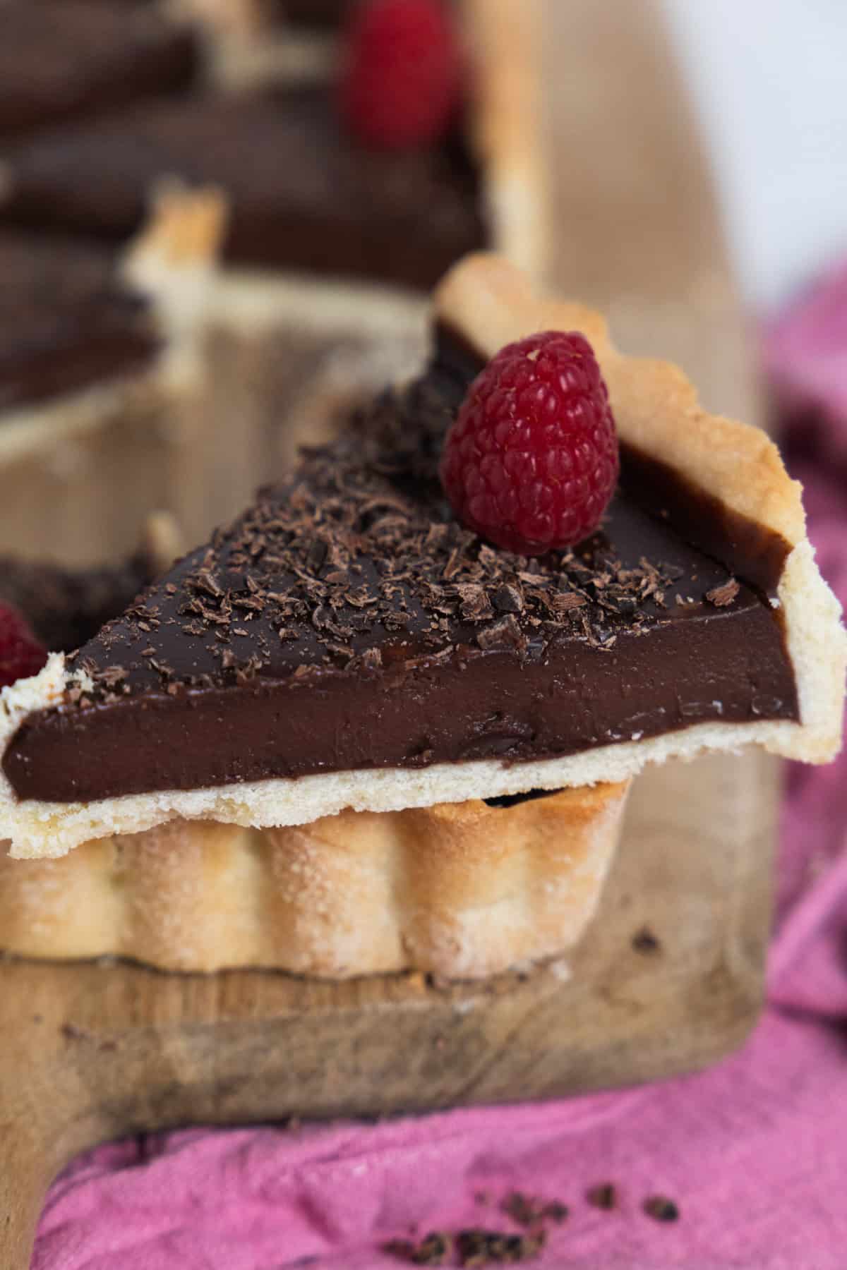Slice of chocolate tart with a raspberry on top. 