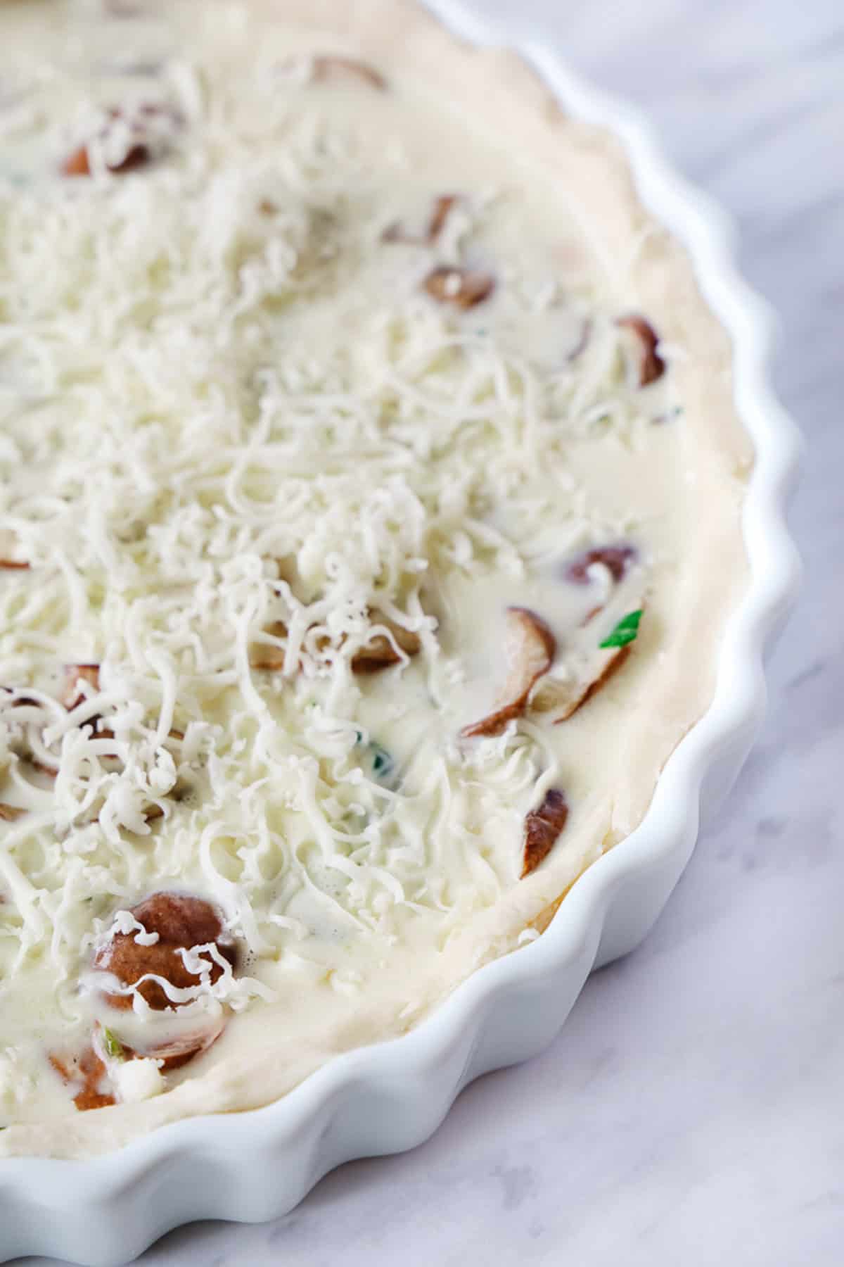 Close up of an uncooked spinach quiche.