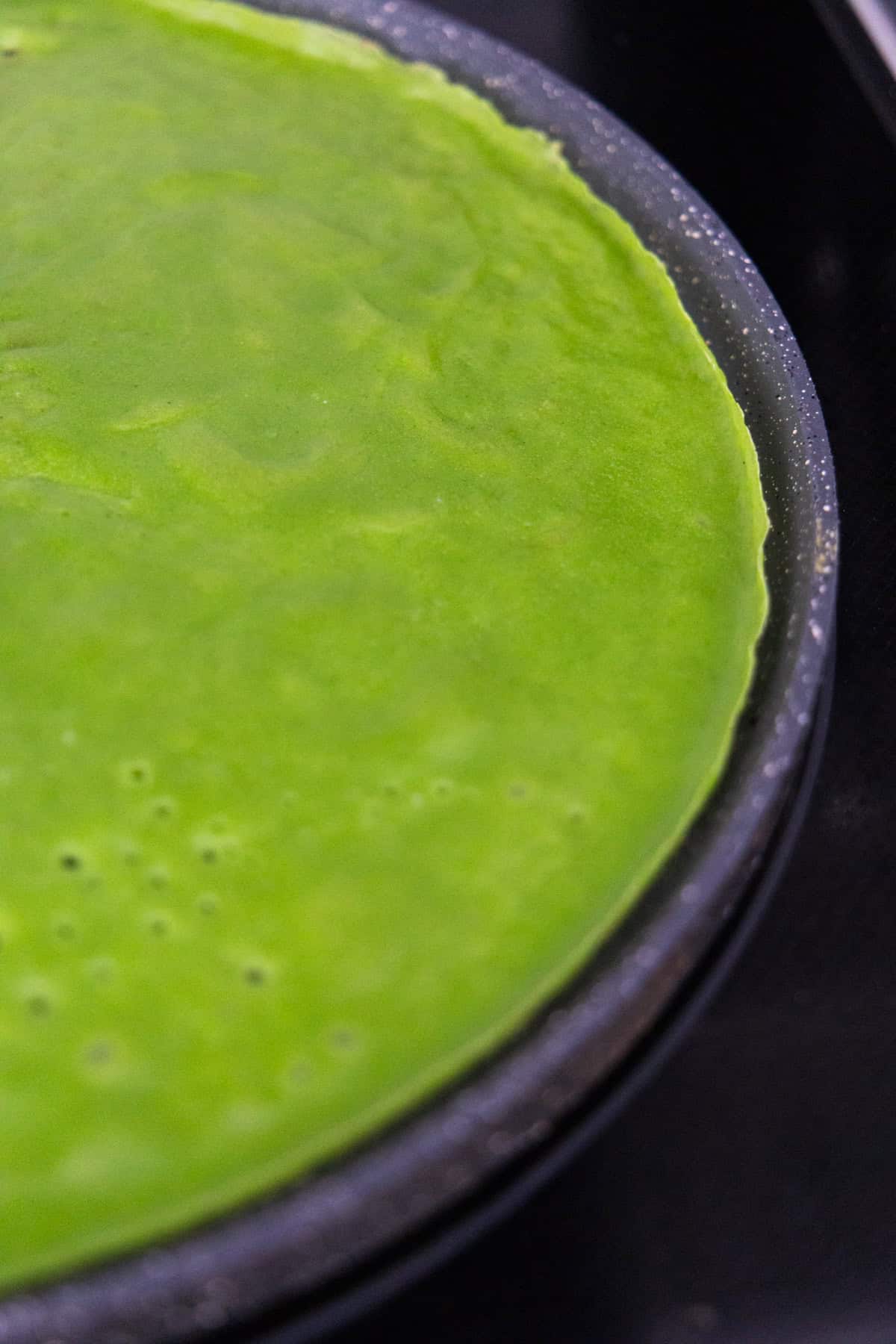 a green french crepes on a black pan. 