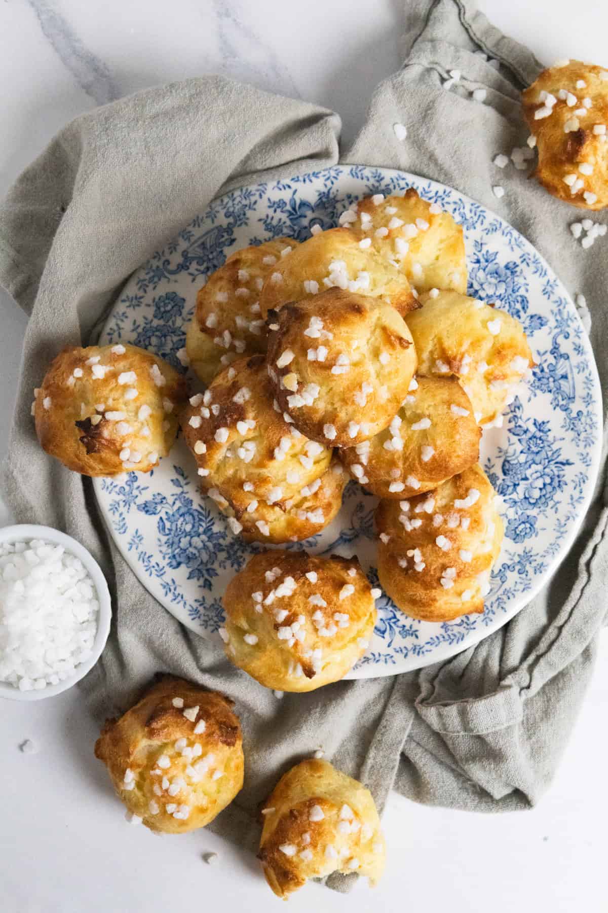chouquettes on a blue plate with a grey tea towel. 